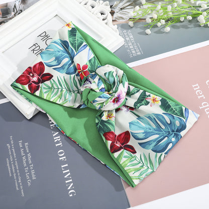 Hairband with tropical floral silk scarf tied in a knot over a green headband
