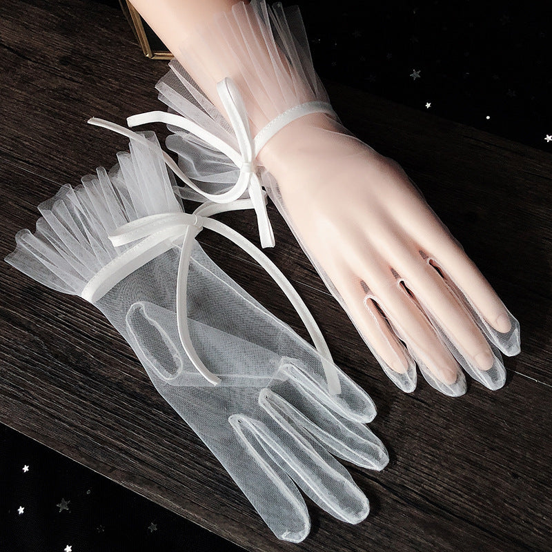 Pair of white sheer bridal gloves with short length, ruffled tulle cuffs and satin ribbon ties
