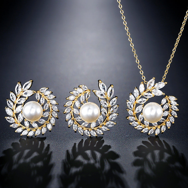 Three-piece jewelry set: gold-tone necklace with pearl-centered pendant and matching crystal-leaf earrings by CJ