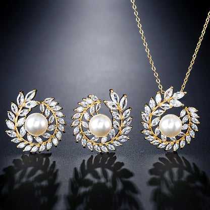 Three-piece jewelry set: gold-tone necklace with pearl-centered pendant and matching crystal-leaf earrings by CJ