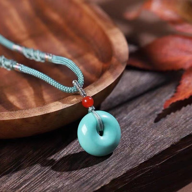 High Porcelain Turquoise Bread Ring Safety Buckle pendant on teal braided cord with glossy glaze and red bead accent