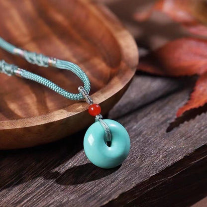 High Porcelain Turquoise Bread Ring Safety Buckle pendant on teal braided cord with glossy glaze and red bead accent