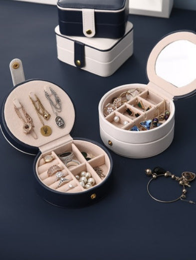 Portable jewelry box by edenista; two round cases with light interiors and mirrors, opened to show rings and earrings