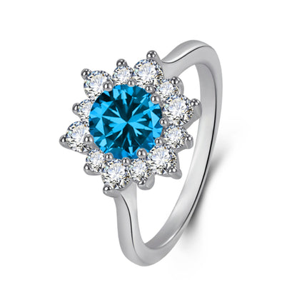 Ring with blue center gemstone encircled by a halo of white diamonds in a silver setting