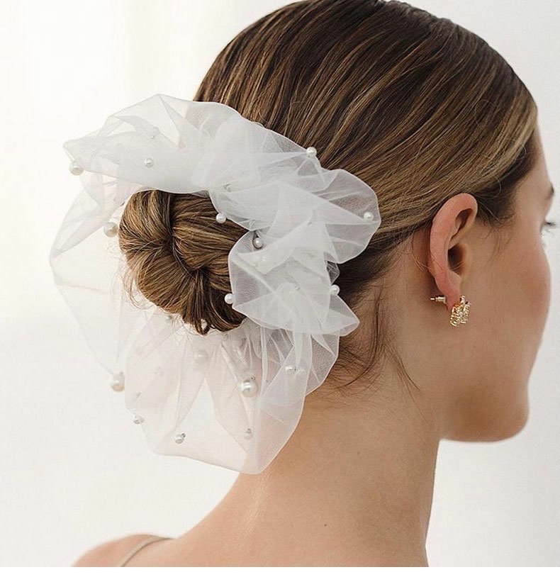 Bridal veil fashion pearl white mesh hairpiece with pearl accents, worn in a neat bun.