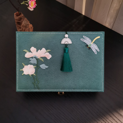 Jewelry box in teal flannel with pink floral embroidery, dragonfly motif, and green tassel