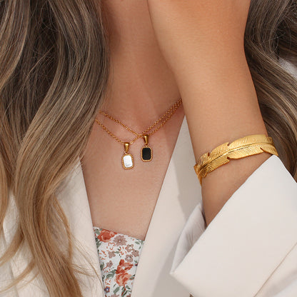 Gold necklace and bracelet on a person with a neutral background