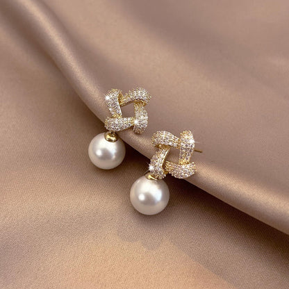 Pair of pearl earrings on a beige fabric background