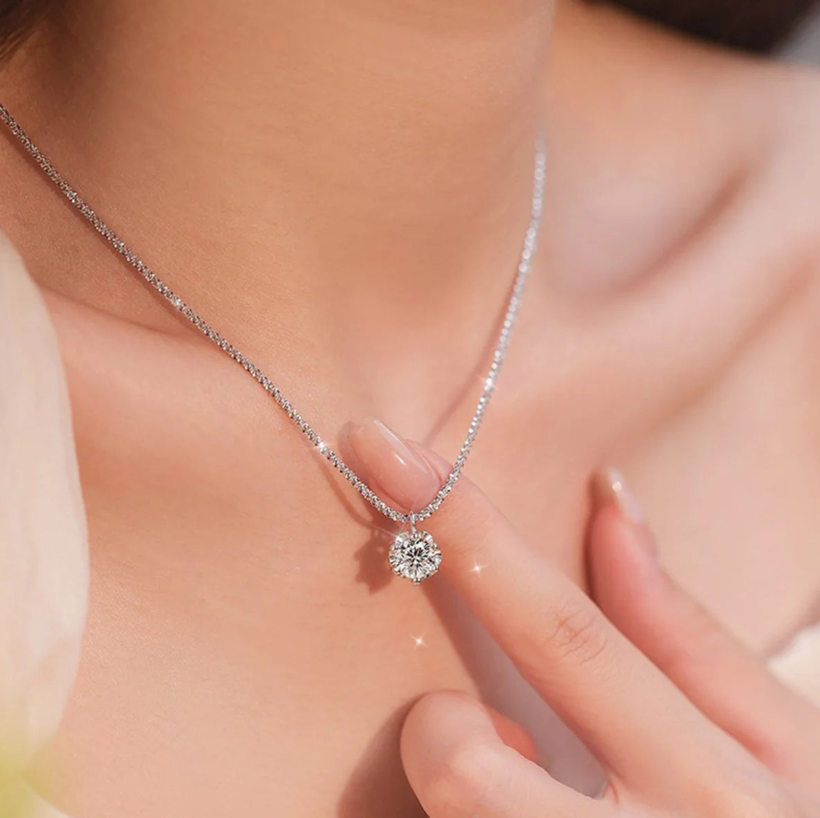 Silver necklace with a diamond pendant on a person's neck