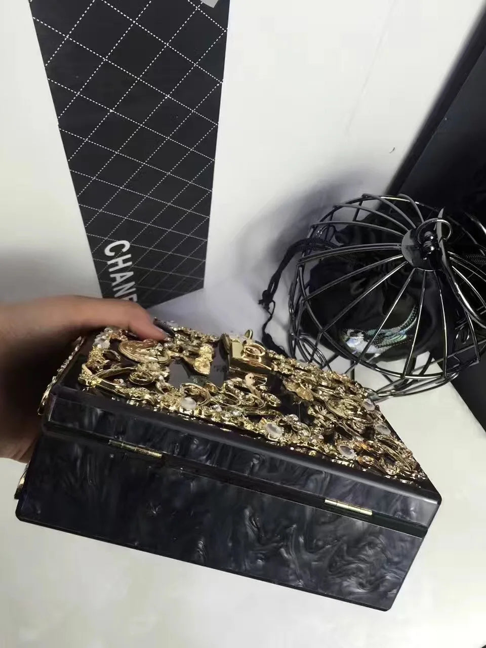 Evening bag with gold rhinestone embellishments on a black marbled acrylic body; clutch style