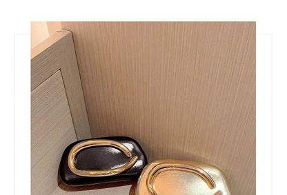 Pair of gold metal-closure box clutch bags in dark red and beige with large curved hardware.