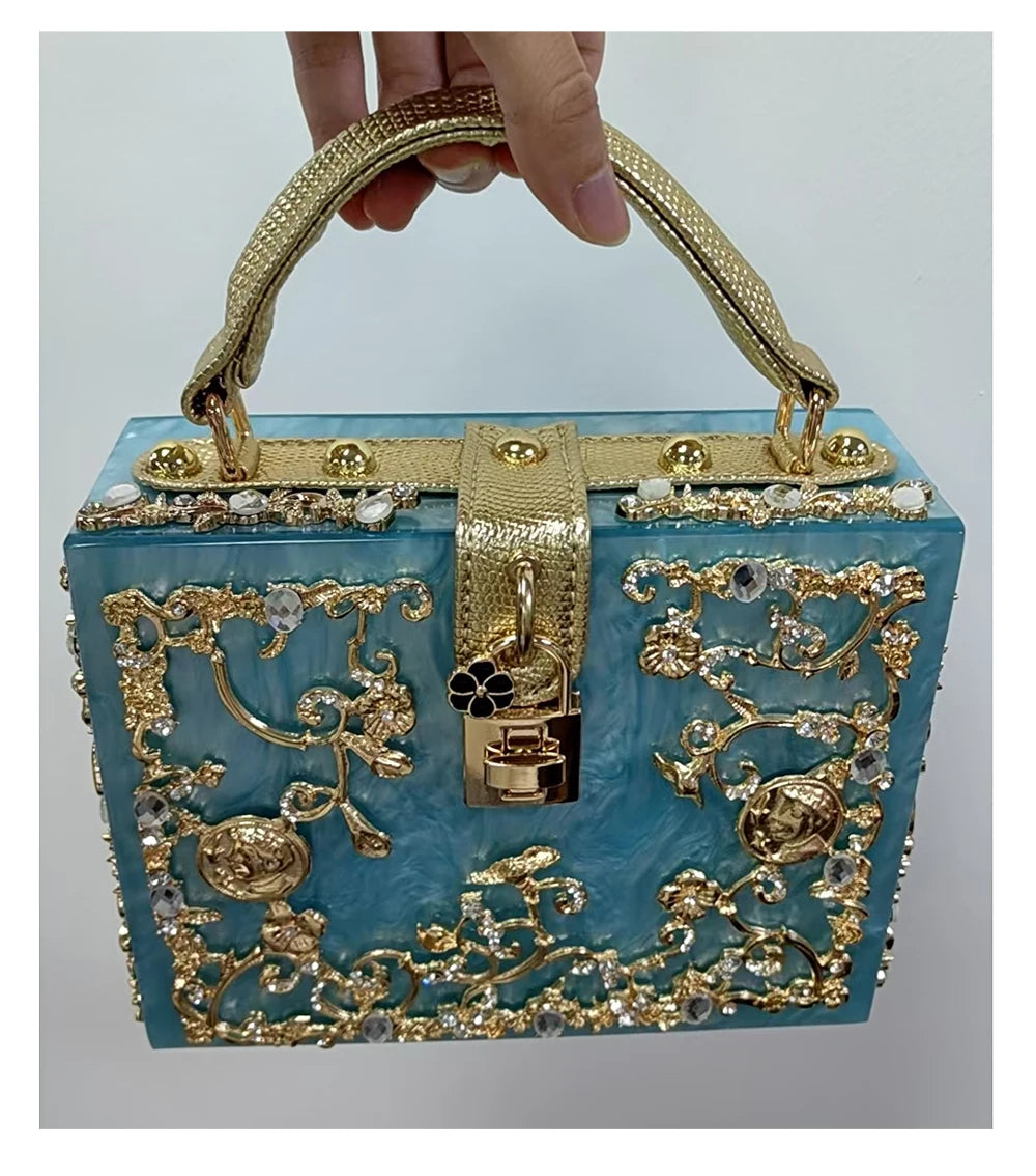 Acrylic evening bag with turquoise body and ornate gold-tone rhinestone filigree, top handle and lock.