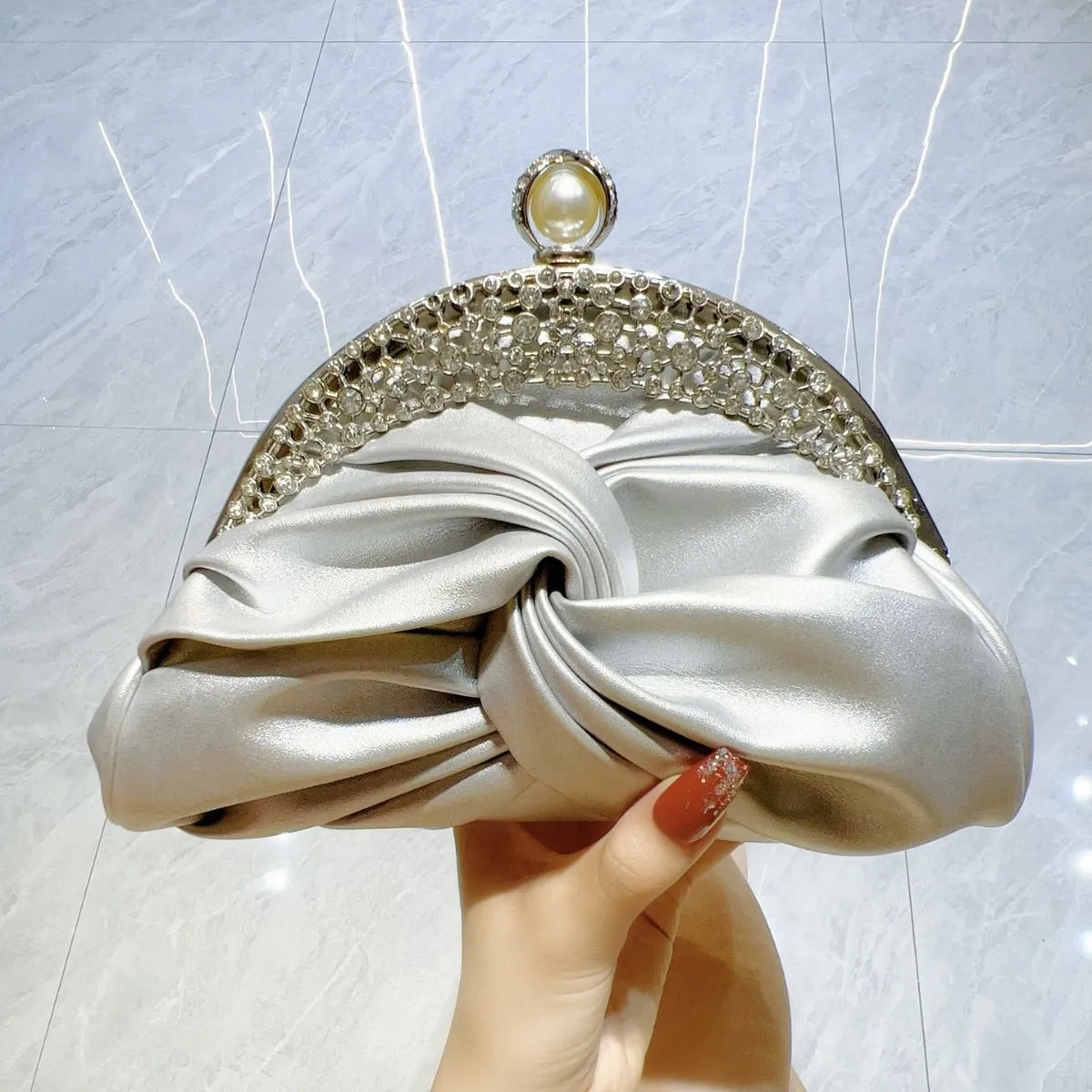 Satin knot clutch by Edenista; silver with crystal-embellished frame and pearl clasp