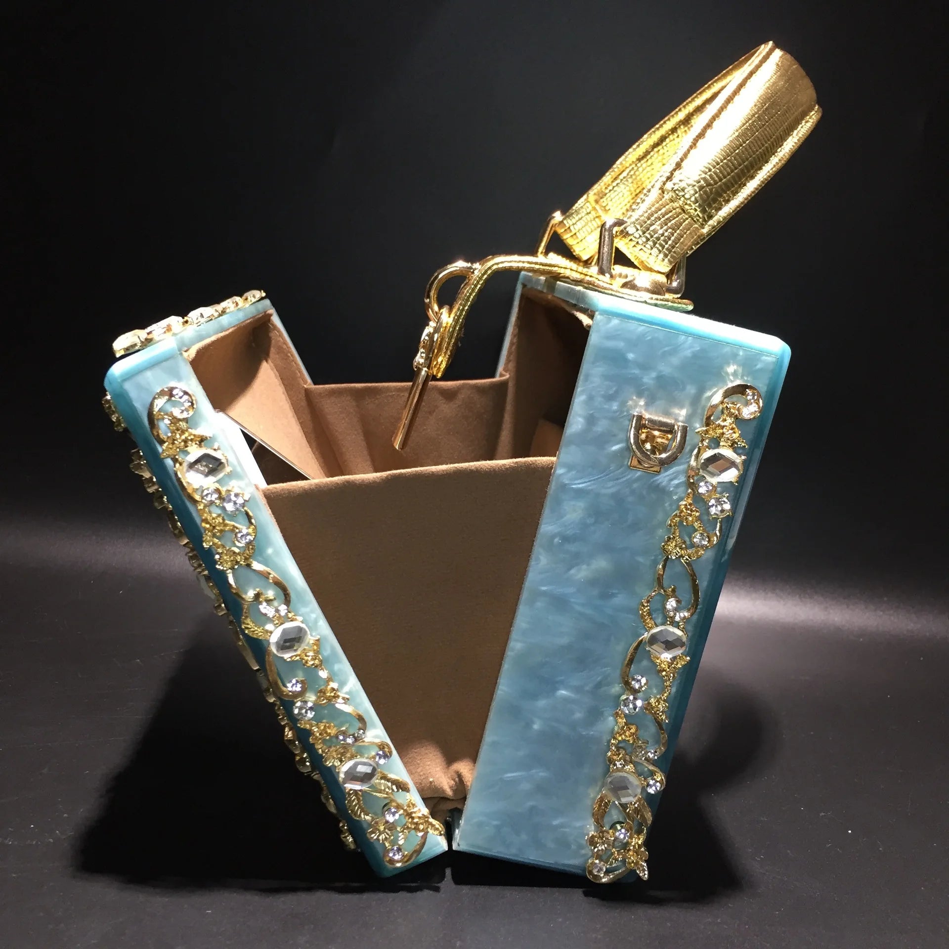 Acrylic evening clutch with turquoise panels, gold rhinestone trim, and brown interior.