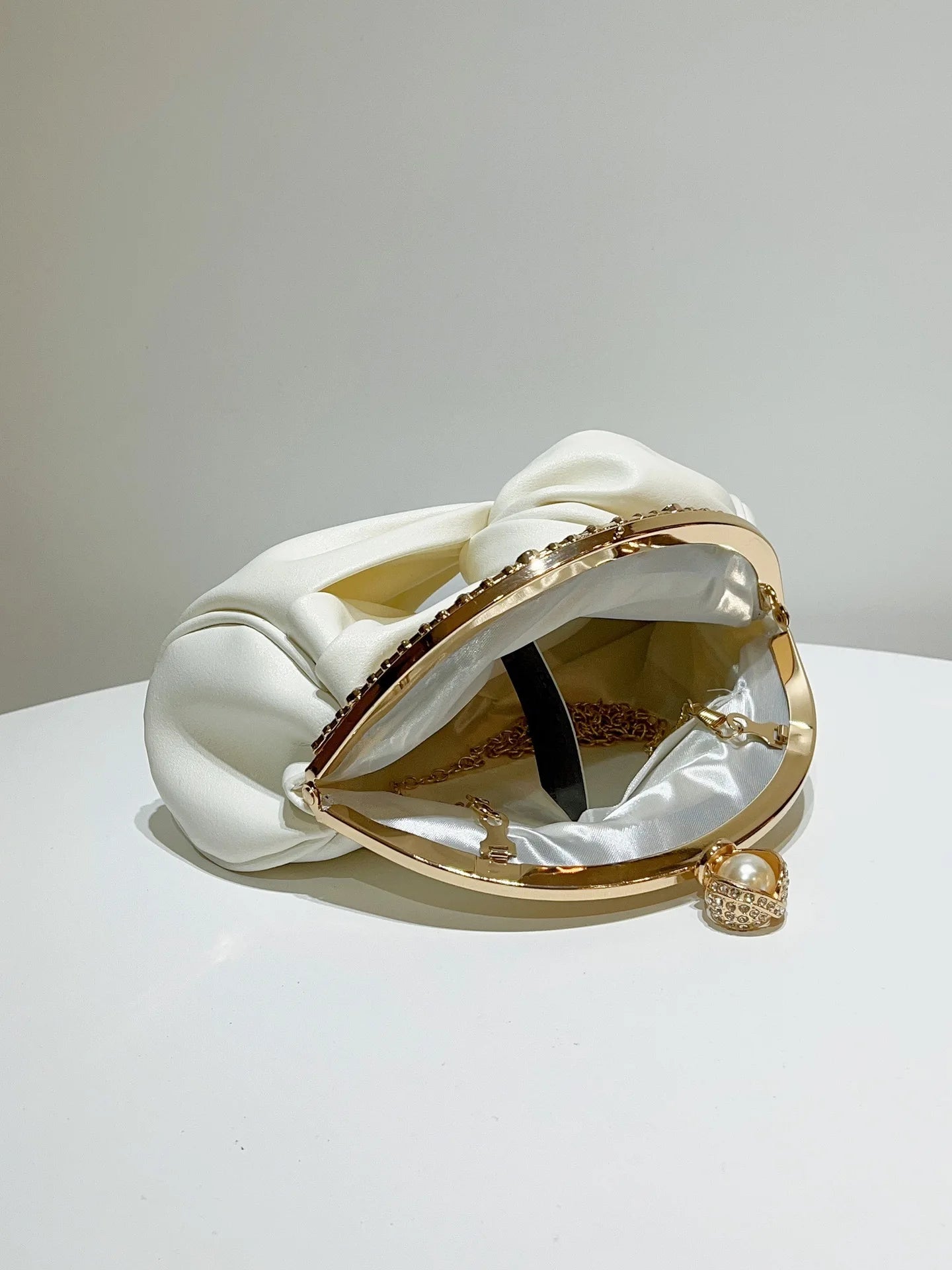 Edenista chain shoulder bag, white satin with knotted top, gold circular frame, chain, and pearl charm