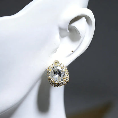 Earrings: large round crystal with halo of small stones in gold-tone setting.