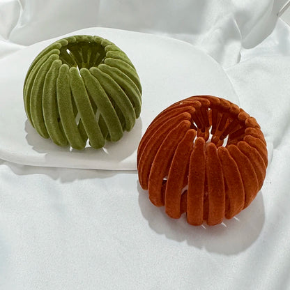 Pair of Edenista velvet hair bun clips, expanding bird-nest accessories in green and orange.