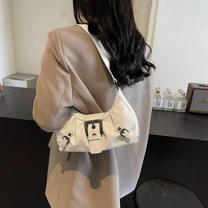 Women's cream hobo handbag with buckle straps, worn over the shoulder