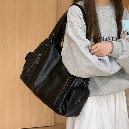 Women's black leather tote bag with large capacity and multiple zippered pockets, shoulder strap