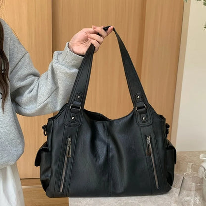 Black leather tote bag with dual handles, exterior zip pockets, and large-capacity multi-pocket design
