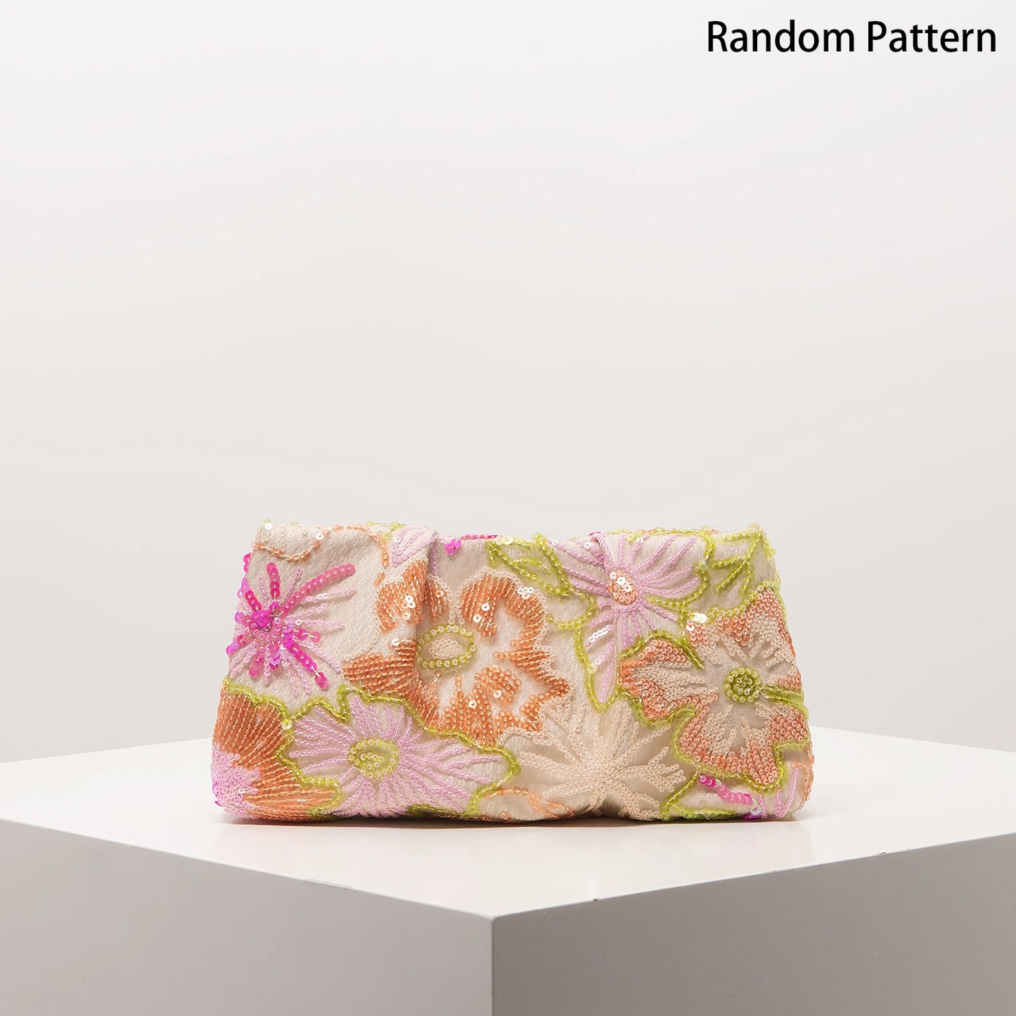 Clutch bag with pastel floral sequin embroidery on pale fabric.
