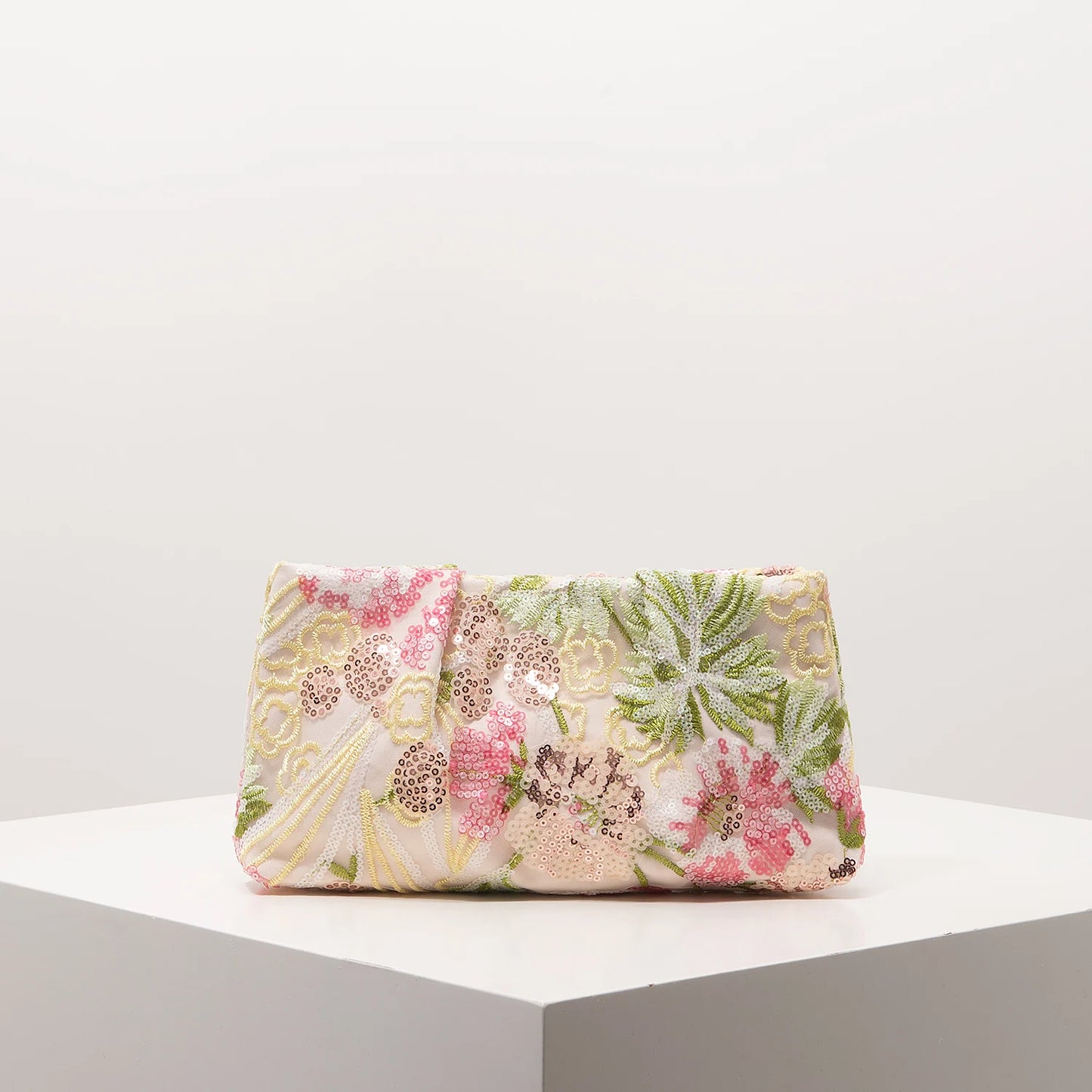 Clutch bag with pink, green and gold floral sequin embroidery on pale pink fabric