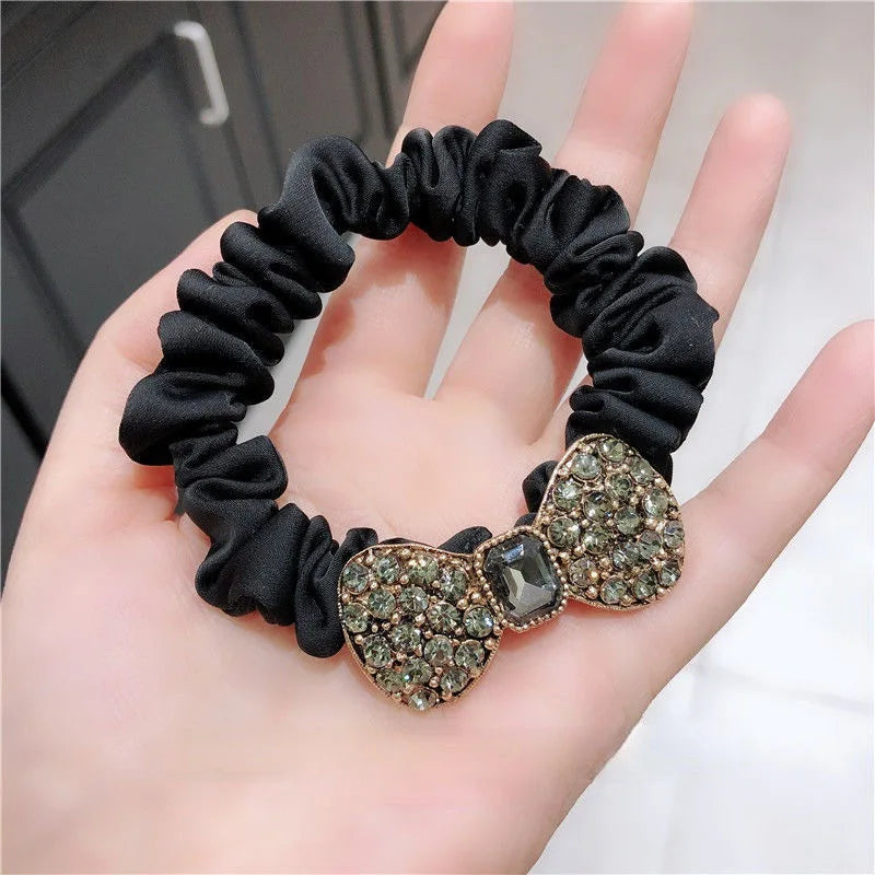 Rhinestone bow scrunchie in black fabric with glittering bow charm