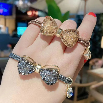 Rhinestone bow scrunchies; two jeweled elastic hair ties in gold-tone and silver-tone.