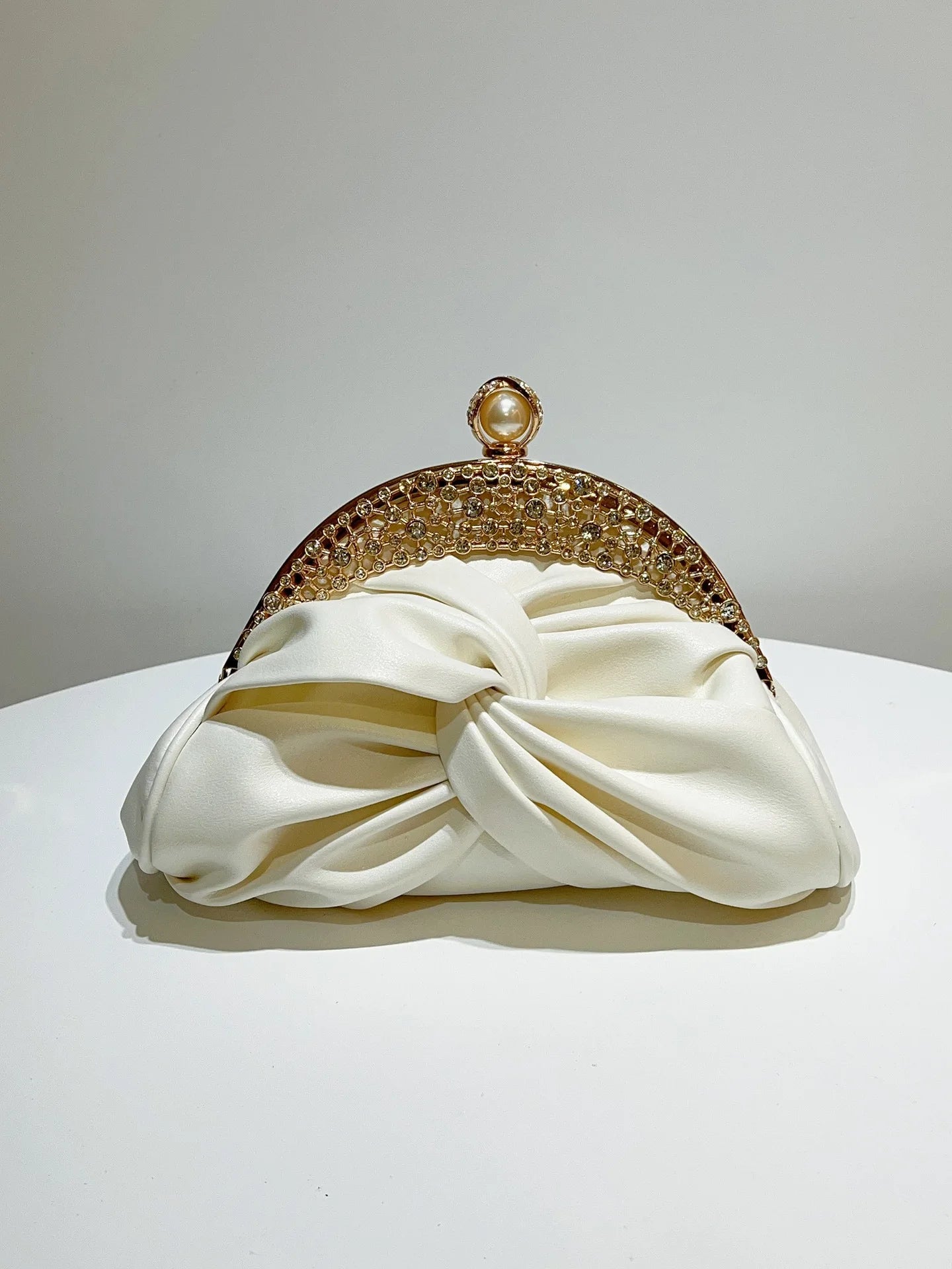 Gold-tone crystal-embellished evening clutch with pearl clasp on ivory satin knot bag