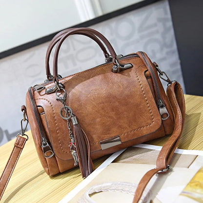 Brown leather retro shoulder bag with floral pendant tassel and top handles.