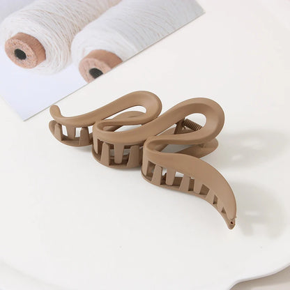 Three large beige acrylic hair claw clips with geometric crab design
