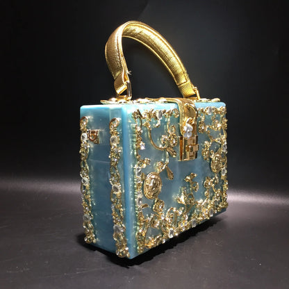 Acrylic evening bag by Edenista in blue with gold rhinestone filigree trim and curved gold handle