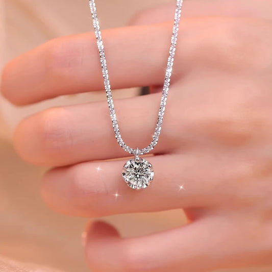Close-up of round brilliant-cut moissanite solitaire pendant on sparkling silver chain held between fingers showing stone brilliance