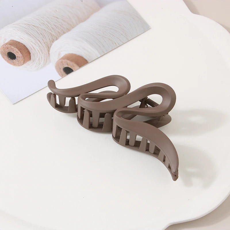 Three beige acrylic large hair claw clips with geometric curved design
