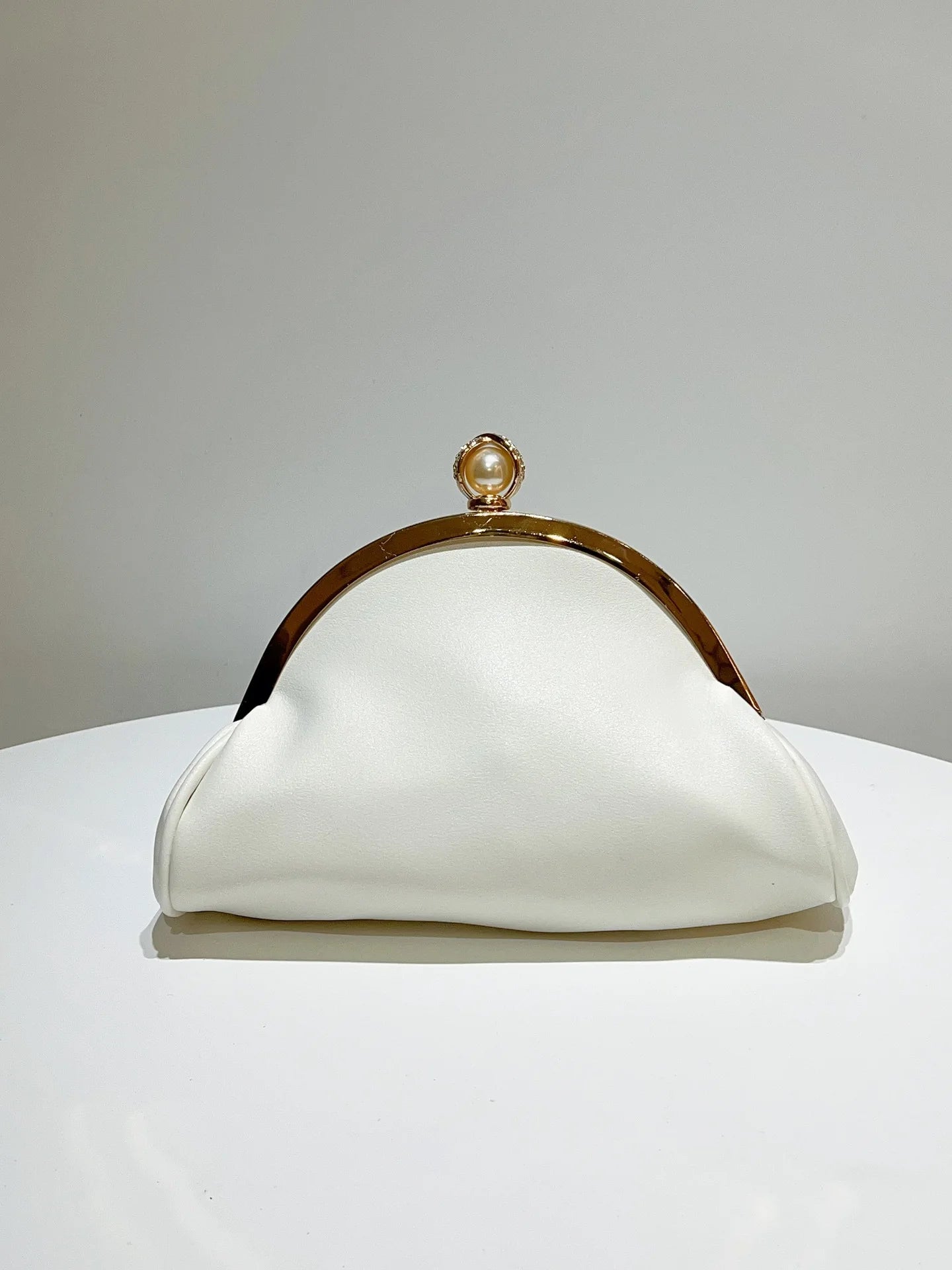 White clutch purse with gold-tone frame and pearl top clasp