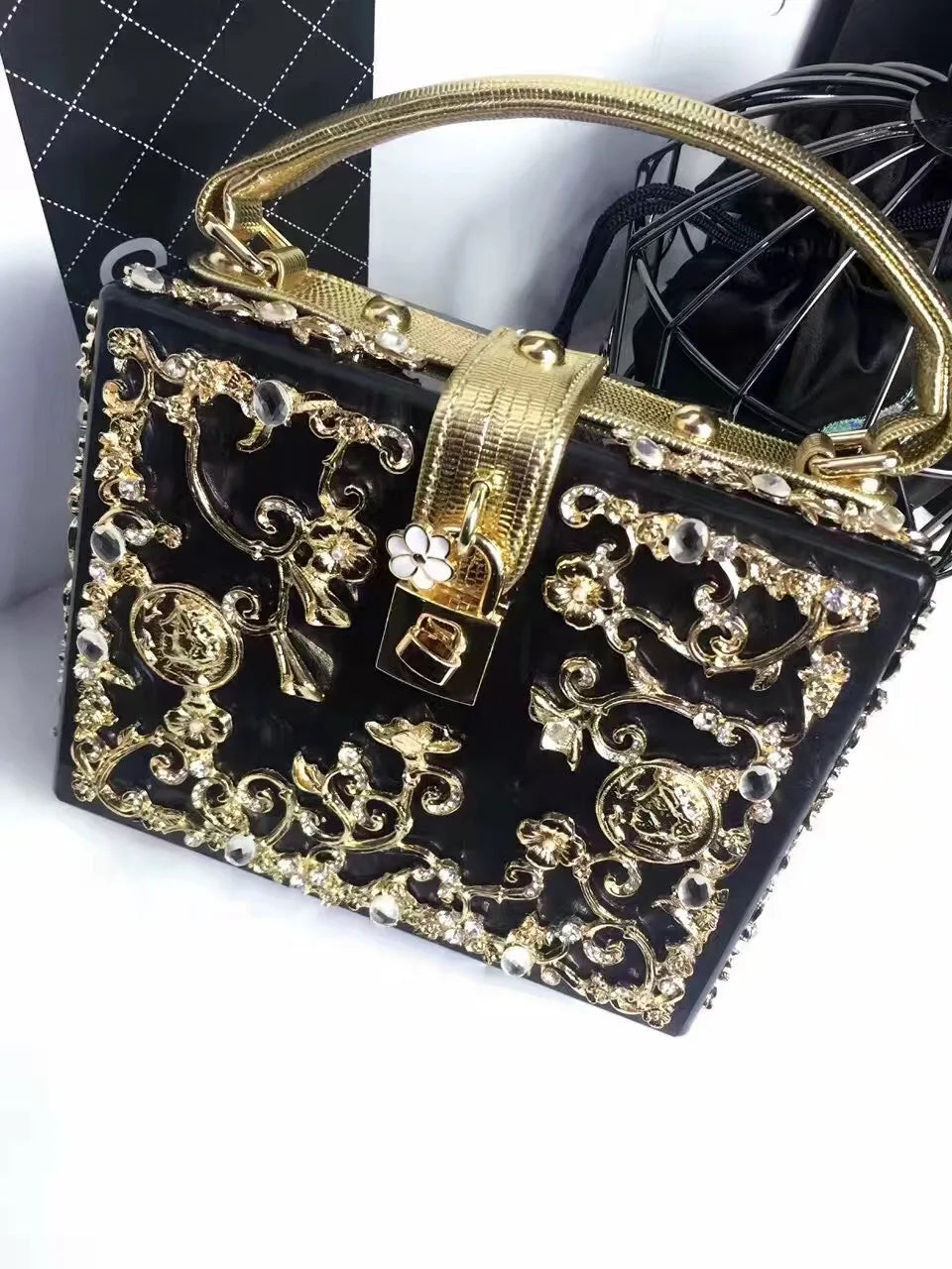 Edenista acrylic evening clutch with ornate gold filigree, black body, gold hardware.