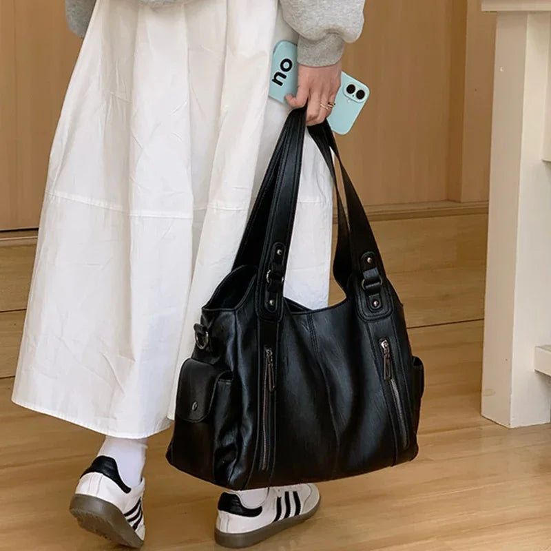 Women's black leather tote bag with multiple pockets and dual top handles