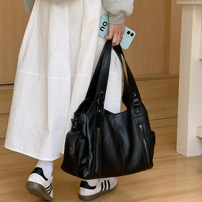 Women's black leather tote bag with multiple pockets and dual top handles