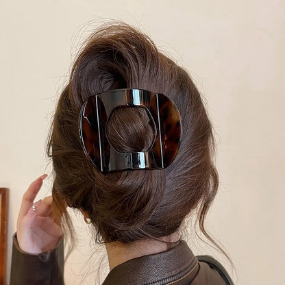 Edenista crab hair clip in dark tortoiseshell, square design with center hole, worn in an updo.