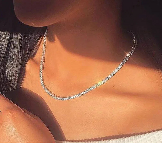 Close-up of a person wearing a silver chain necklace with sunlight casting shadows.