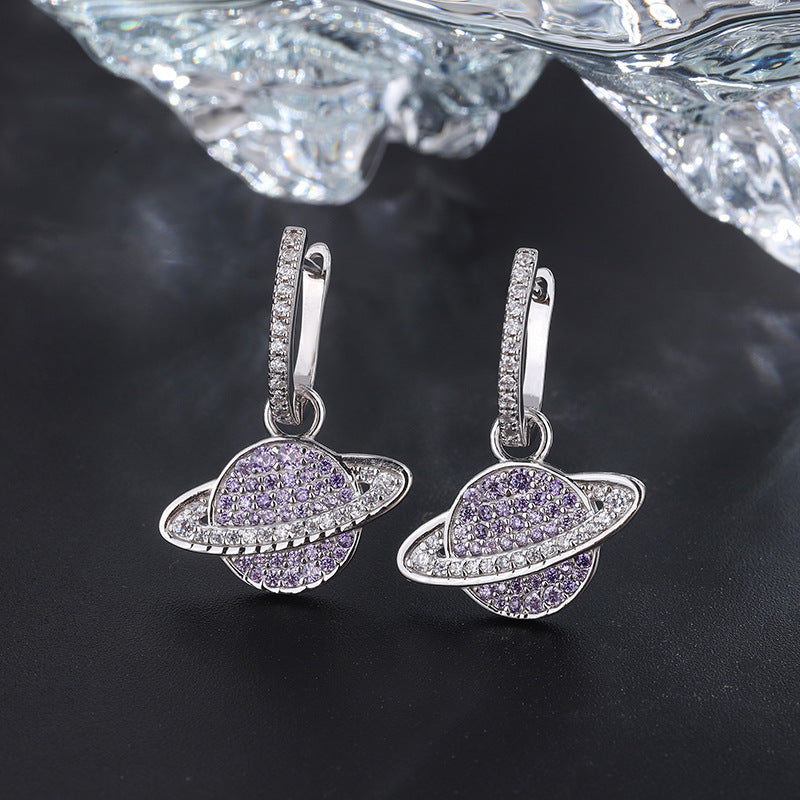 Silver earrings with purple gemstones on a dark background