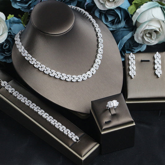 Bridal zircon jewelry four-piece set with silver-tone necklace, bracelet, earrings, and ring on display.