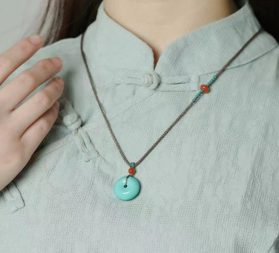 Necklace with turquoise circular pendant and orange accent beads on a metal chain (CJ brand)