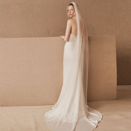 Beading veil, cj brand, long sheer white bridal veil with bead-trim over a strapless gown.