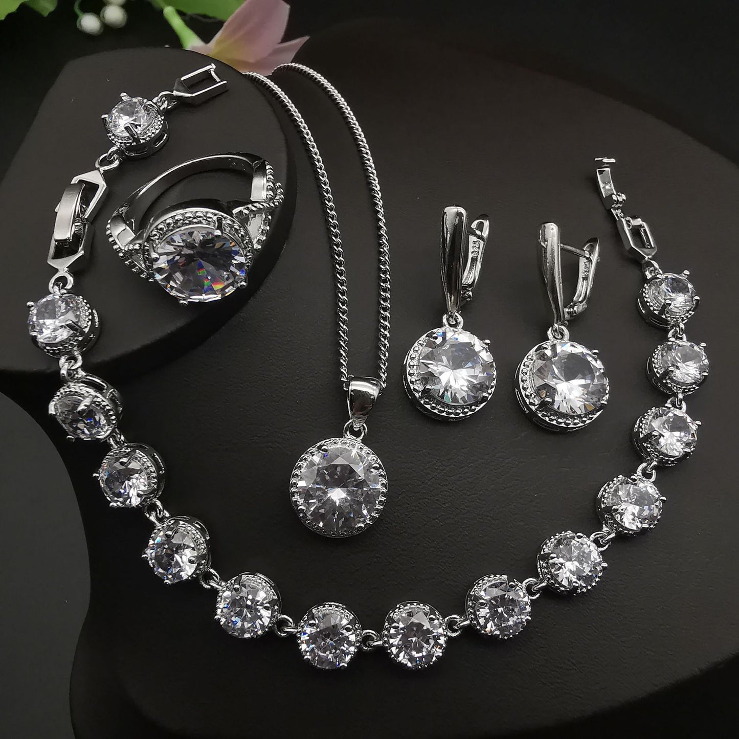 Silver-tone four-piece jewelry set with round crystal stones by cj: ring, necklace, bracelet, and earrings.