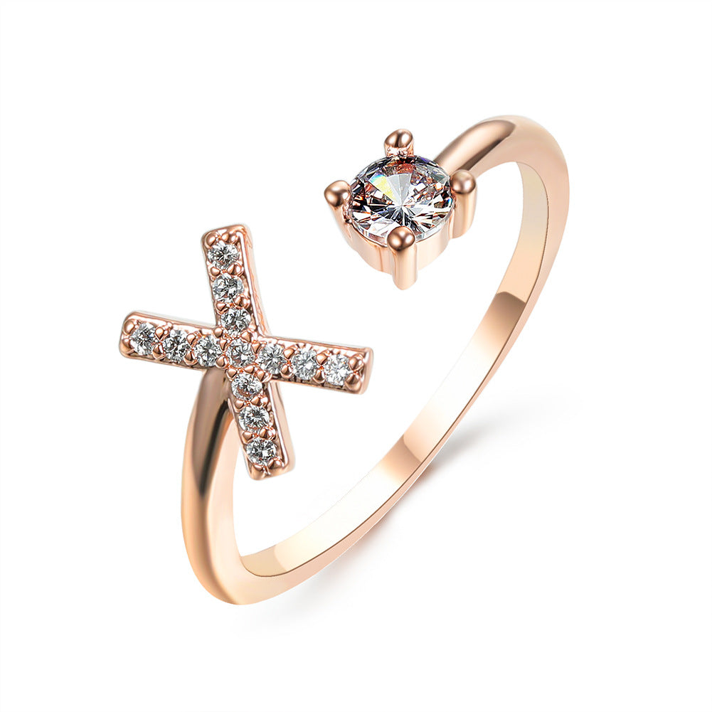Ring in rose gold; adjustable band with a crystal-studded cross and a solitaire stone.