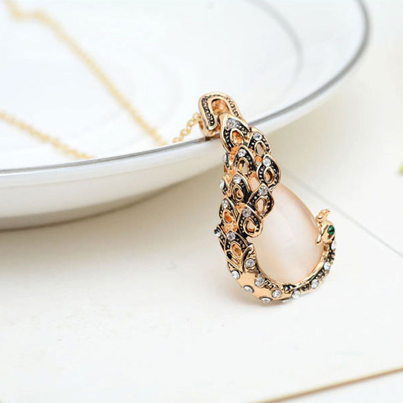 Peacock pendant necklace in gold-tone with crystal accents and peach-colored centerpiece
