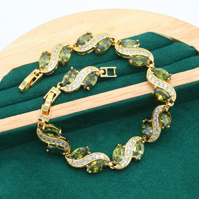 Gold bracelet with green zircon stones and clear pavé crystal links.