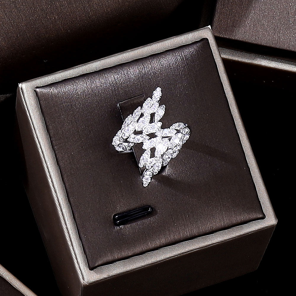 Ring with zircon crystals on silver-tone metal, displayed on a dark jewelry box.