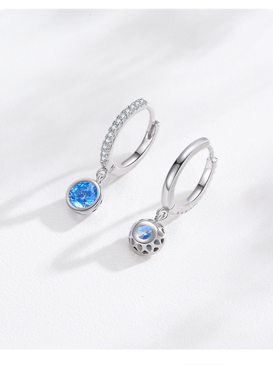 Pair of silver hoop earrings with sea blue stones; one pave-crystal hoop and one lattice-ball charm